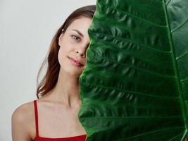 pretty woman in red swimsuit big green leaf close-up photo