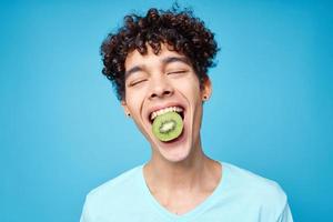 hermoso hombre con kiwi Rizado pelo en su boca recortado ver en azul antecedentes foto