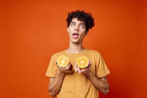 curly guy in a yellow t-shirt oranges in his hands red background photo