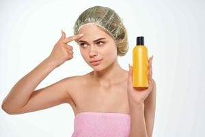 woman in pink towel with cap on her head lotion skin care photo