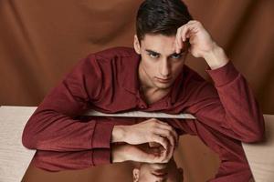Man at the table near the mirror reflection model brown shirt fabric background photo