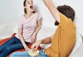 hombre con platos palomitas de maiz y mujer en naranja tartán sofá familia amigos teniendo divertido foto