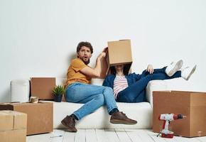 family young couple on the couch fun moving boxes with things photo