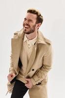 Cheerful man in beige coat emotions autumn style light background photo
