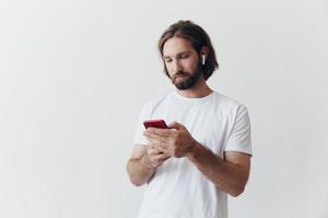 Man blogger holds a phone in his hands and communicates with people online in social networks with a smile and a white t-shirt on a white background photo