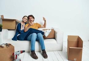 joven Pareja sentado en blanco sofá cajas Moviente estilo de vida foto