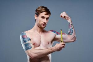 young man with tattoo and tape measure inflated muscles fitness bodybuilder model photo