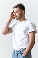 Portrait shot of handsome pensive romantic serious tanned man guy in basic t-shirt looks aside posing on white background. Fashion Style New Collection Offer. Copy space for ad. Model snap photo