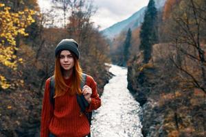 mujer con manos elevado arriba en naturaleza en el montañas otoño bosque foto