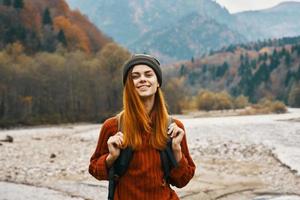 contento mujer en otoño bosque en el montañas al aire libre con un mochila en su espalda viaje turismo foto