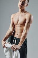 sporty man with towel in hands pumped up press workout isolated background studio photo