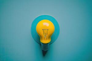 flat lay photo of yellow bulb on turquoise blue background. Illustration