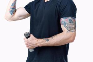 hombre en negro camiseta con tatuaje en su brazo y pesas músculo carrocero foto