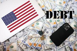 Debt concept. USA flag, dollar money with keys, laptop and phone background. photo