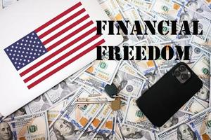 Financial freedom concept. USA flag, dollar money with keys, laptop and phone background. photo