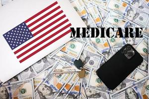 Medicare concept. USA flag, dollar money with keys, laptop and phone background. photo