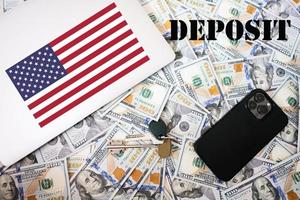 Deposit concept. USA flag, dollar money with keys, laptop and phone background. photo