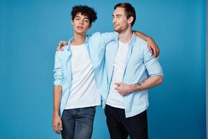 young men in blue shirts hugging on isolated background friends fun photo