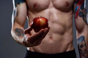 desnudo carrocero con bombeado músculos y tatuaje manzana en mano salud foto