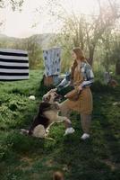 mujer acariciando su grande peludo perro en. granja en el campo en contra un fondo de limpiar lavandería en un cuerda foto