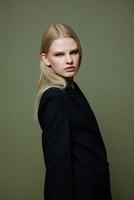 An attractive girl turns into the camera from behind her shoulder. Cool model posing on a green background in the studio photo