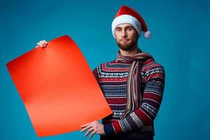 Cheerful man in a santa hat holding a banner holiday blue background photo