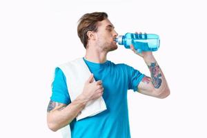 man athlete drinks water from a bottle on a white background and a towel on his shoulder photo