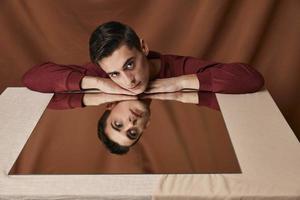 man sitting at the table and mirror reflection fabric background photo