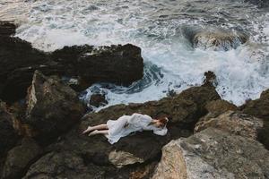 woman in a secluded spot on a wild rocky coast in a white dress vacation concept photo