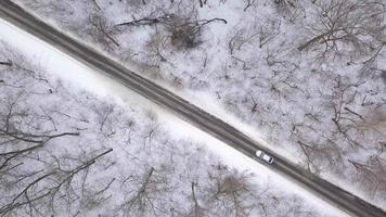 Aerial view on cars driving through winter forest road. Scenic winter landscape video