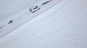 aéreo Visão em carro dirigindo através inverno floresta estrada entre a coberto de neve Campos video