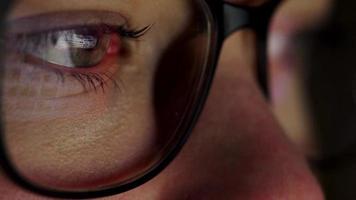 Woman in glasses looking on the monitor and surfing Internet. The monitor screen is reflected in the glasses video