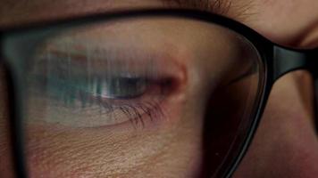 Woman in glasses looking on the monitor and surfing Internet. The monitor screen is reflected in the glasses video