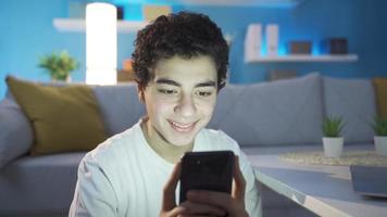 jongen gebruik makend van smartphone is sms'en. de jong persoon gebruik makend van een slim telefoon alleen Bij nacht is sms'en, aan het doen Onderzoek Aan de internetten, surfing de media met sociaal media. video