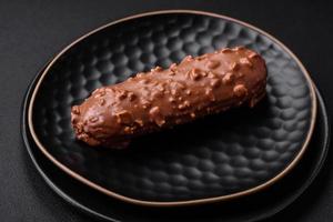 Delicious fresh eclair cake or profiterole with chocolate and nuts photo