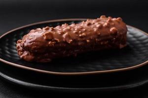 Delicious fresh eclair cake or profiterole with chocolate and nuts photo