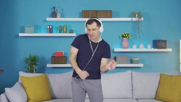 The fun guy is dancing alone at home listening to music. The man immerses himself in the music in a playful way and begins to dance. video