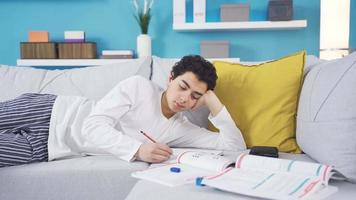 gelukkig mannetje leerling aan het studeren in een ontspannen staat resting Aan de bank. schattig en knap mannetje leerling is gelukkig naar studie comfortabel Bij huis. video