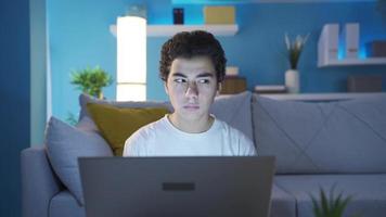 confuso adolescente Garoto olhando às computador portátil com duvida e apreensões. adolescente adolescente usando computador portátil sozinho às lar, olhando às computador portátil às casa muito cautelosamente e suspeitosamente. video