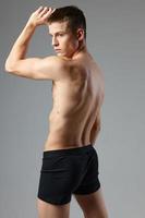 sporty man with pumped up naked body black panties posing exercise photo