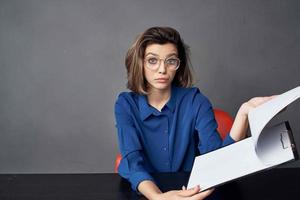 Business woman sits at a work table folder in hands Copy Space photo