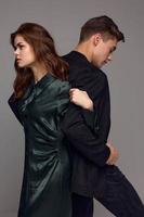 An elegant woman holds the hand of a man in a suit on a gray background with backs to each other photo