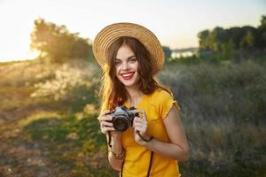 mujer fotógrafo cámara en manos sonrisa rojo labios sombrero atractivo Mira naturaleza foto