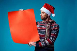 Cheerful man in a santa hat holding a banner holiday blue background photo