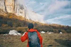 traveler with backpack in autumn in the mountains blue sky clouds high rocks landscape