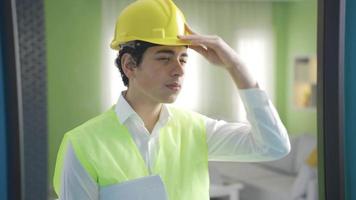 el chico en un casco y chaleco Sueños de siendo un ingeniero en frente de el espejo. linda chico mirando a él mismo en frente de el espejo vestido como un ingeniero a hogar. futuro ingeniero. video