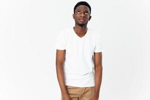 happy african man in white t-shirt and beige pants on light background photo