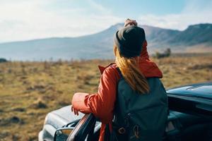 viajero en un sombrero con un mochila cerca el coche puerta en naturaleza foto