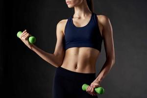 sports figure of a woman with dumbbells in hands exercises motivation dark background photo