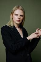 Portrait of a stunning elegant girl in a black suit posing professionally on a green background in the studio. The concept of advertising for designer brands photo